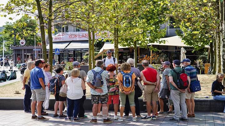 Mensen op plein luisteren naar rondleider